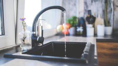 Grifo de cocina con agua corriendo sobre un fregadero moderno