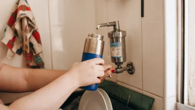 Filtro de agua instalado en el grifo de la cocina mientras se llena una botella